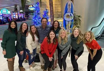Dental team members posing together in modern office lobby with holiday decorations.
